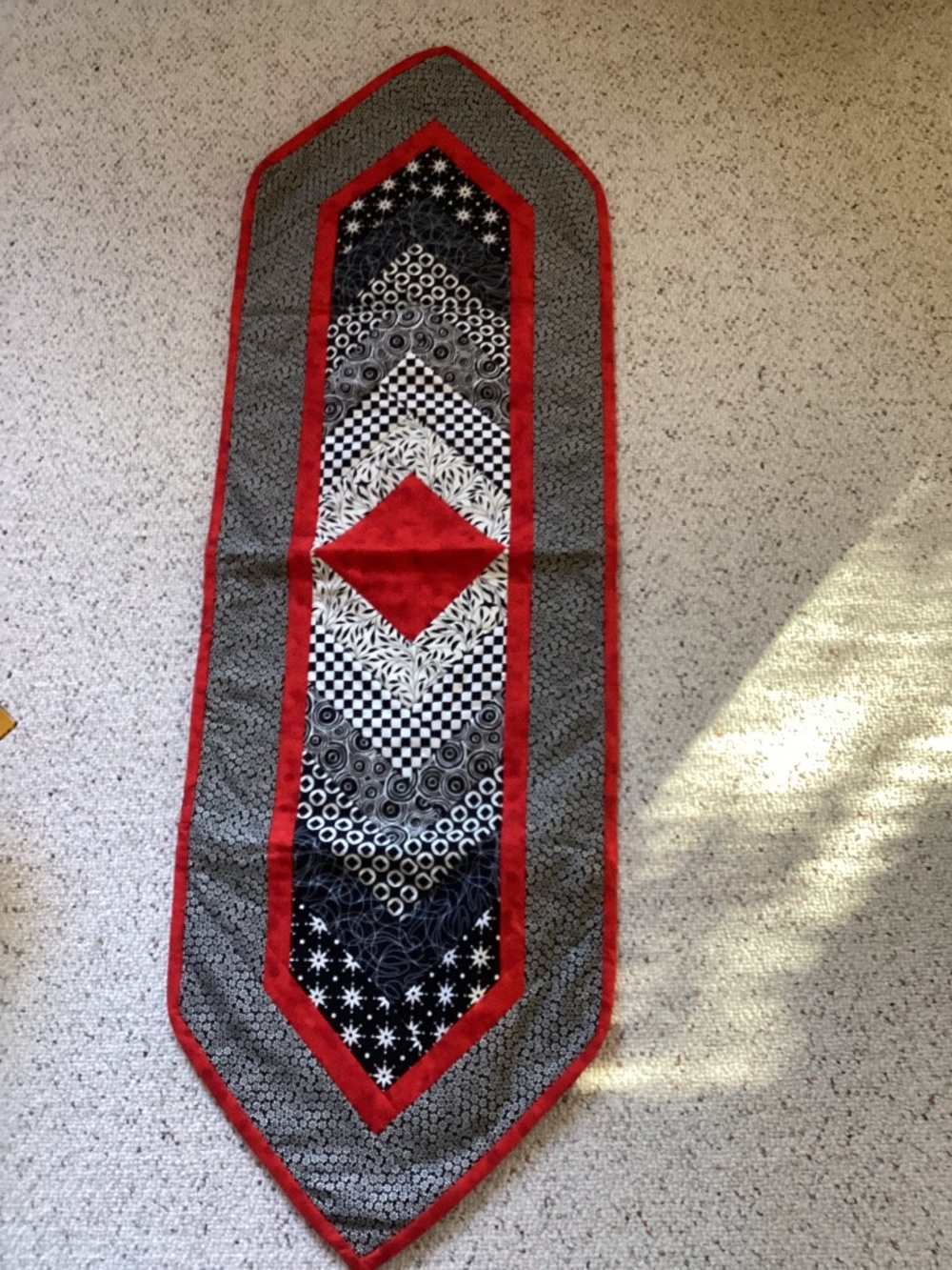 Machine quilted table runner in black prints and red accents Approx. 50 inches